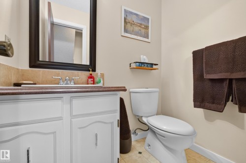 Bathroom featuring a white vanity with paneling, a dark countertop, an integrated sink, and a framed mirror - 12062 157 Avenue, Edmonton, AB 
