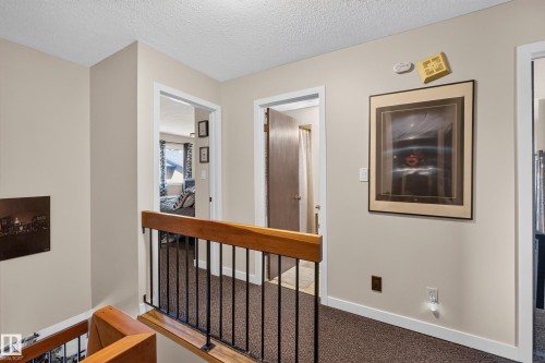 Upper-level hallway featuring a textured ceiling, neutral wall paint, and white baseboards - 12062 157 Avenue, Edmonton, AB 