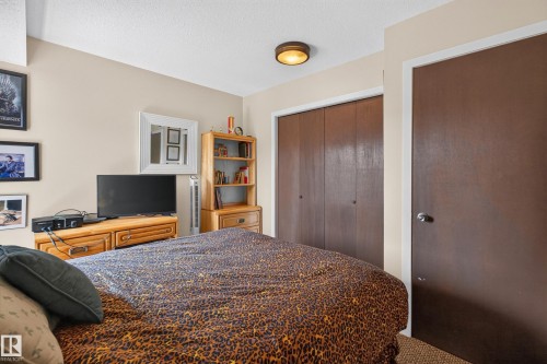 Bedroom featuring neutral wall paint, a built-in closet with brown bi-fold doors, and a round ceiling light fixture - 12062 157 Avenue, Edmonton, AB 