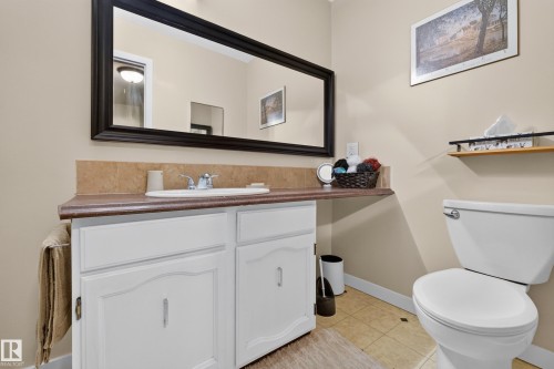 Bathroom featuring a white vanity with a laminate countertop, integrated sink, and chrome faucet - 12062 157 Avenue, Edmonton, AB 
