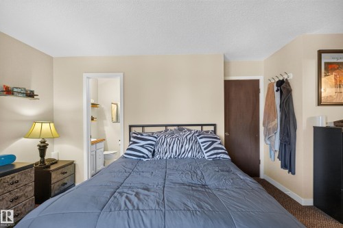 Bedroom featuring a metal bed frame, light beige walls, and brown carpet flooring - 12062 157 Avenue, Edmonton, AB 