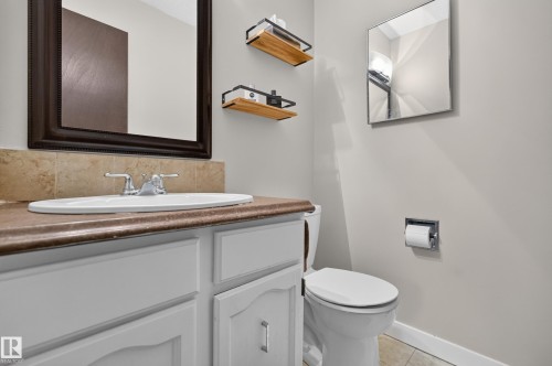Bathroom vanity featuring a drop-in sink with chrome faucet, a brown countertop, and light-toned cabinetry - 12062 157 Avenue, Edmonton, AB 