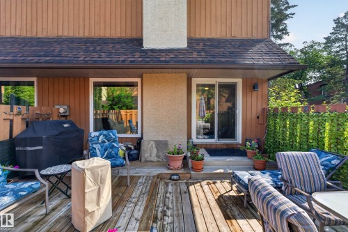 Wood deck featuring a privacy screen, sliding glass door, and exterior sconce lighting - 12062 157 Avenue, Edmonton, AB 