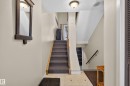 Entryway featuring tile flooring, a carpeted staircase with wood handrails, and a ceiling-mounted light fixture - 12062 157 Avenue, Edmonton, AB 