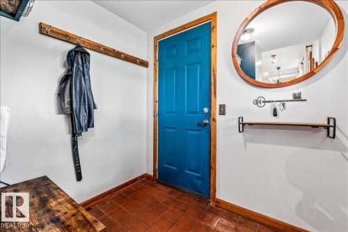 Entryway featuring a vibrant blue door with natural wood trim, terracotta floor tiling, and white wall finishes - 11603 70 Street Nw, Edmonton, AB 