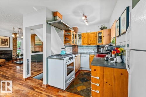 Kitchen featuring natural wood cabinetry, a white gas range, and slate-style floor tiles - 11603 70 Street Nw, Edmonton, AB 