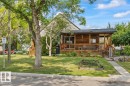 Front exterior with a covered wood deck, wood siding, and mature trees - 11603 70 Street Nw, Edmonton, AB 