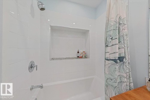 Bathtub and shower combination featuring white subway tile surround, recessed shower niche, and chrome fixtures - 11603 70 Street Nw, Edmonton, AB 