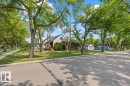 Charming home featuring a pitched roof, front porch, mature trees, manicured lawn, and a detached garage - 11603 70 Street Nw, Edmonton, AB 