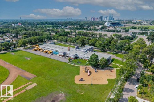 Expansive property featuring a large institutional building, an athletic field, a playground area, and mature trees - 11603 70 Street Nw, Edmonton, AB 