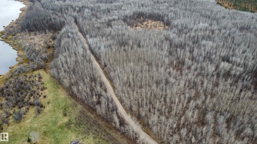 Expansive wooded acreage featuring a natural water body boundary and a defined dirt trail - Rge Rd 62, Rural Barrhead County, AB 