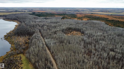 Expansive land parcel featuring a significant body of water, extensive tree coverage, varied foliage, and a defined ground path - Rge Rd 62, Rural Barrhead County, AB 