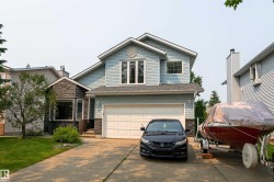 Two-story residence featuring light blue siding and dark stone facade accents - 