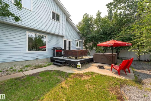 Rear exterior featuring light blue siding, a ground-level deck, and a concrete patio - 14 Durand Place, St. Albert, AB 