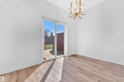 Spacious room featuring wood-finish flooring, white walls with wainscoting, and a modern gold-toned geometric chandelier - 