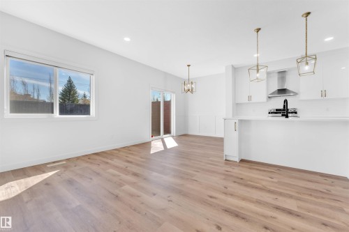 Open-concept living area with wood-finish flooring, recessed lighting, and a modern kitchen - 523 Kleins Court, Leduc, AB - Indoor