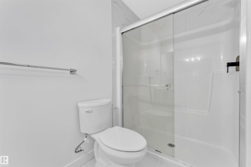 Modern bathroom featuring a glass-enclosed shower with sliding door, white acrylic shower surround, and a sleek commode - 523 Kleins Court, Leduc, AB - Indoor Photo Showing Bathroom