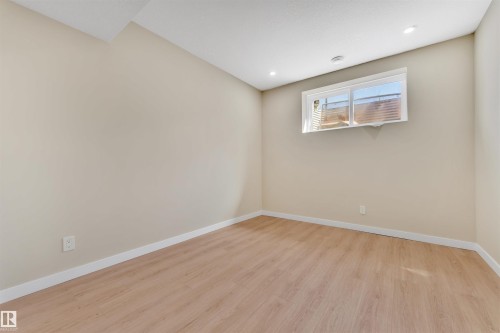 Neutral-toned room featuring wood-finish flooring, a white trim baseboard, and a white ceiling with recessed lighting - 523 Kleins Court, Leduc, AB - Indoor Photo Showing Other Room