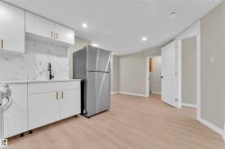 Compact kitchen area featuring white cabinetry, gold-tone hardware, and a white marble-patterned backsplash - 