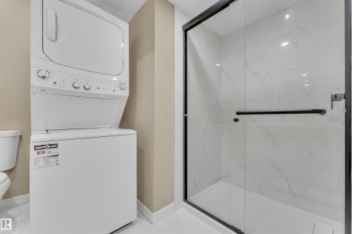 Walk-in shower featuring a frameless glass enclosure and black trim - 523 Kleins Court, Leduc, AB - Indoor Photo Showing Laundry Room