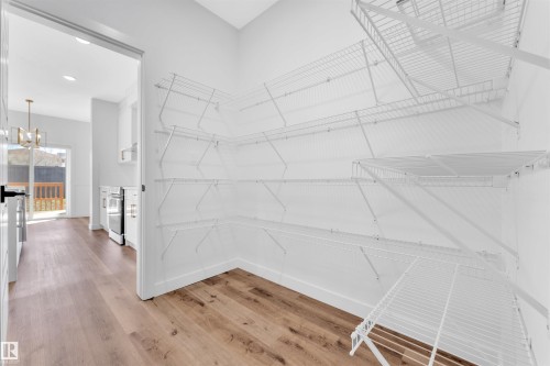 Corner pantry with white wire shelving, wood-finish flooring, and a white baseboard trim - 523 Kleins Court, Leduc, AB - Indoor