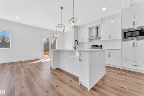 Kitchen featuring a central island, white cabinetry, and wood-finish flooring - 523 Kleins Court, Leduc, AB - Indoor Photo Showing Kitchen With Upgraded Kitchen