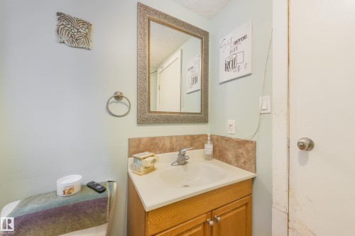 Bathroom vanity featuring a light wood cabinet, integrated sink, and a framed mirror - 17328 106 Street, Edmonton, AB 