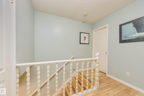 Staircase featuring wood-finish flooring and a white baluster railing - 17328 106 Street, Edmonton, AB 