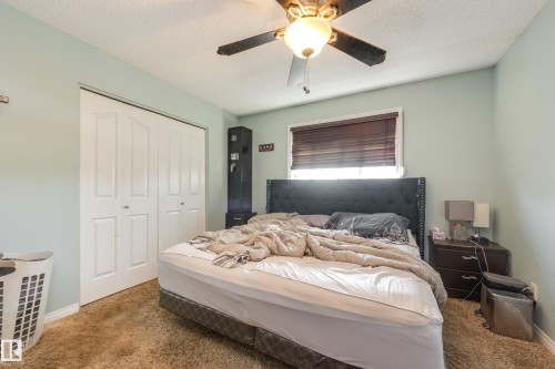 Bedroom featuring textured carpeting, a ceiling fan with integrated lighting, and a window with blinds - 17328 106 Street, Edmonton, AB 