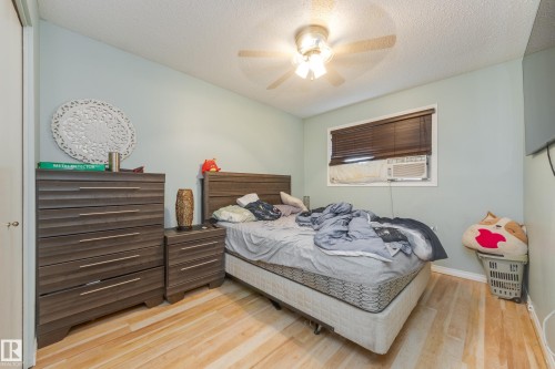 Bedroom featuring wood-finish flooring, a window with horizontal blinds, and a ceiling fan with integrated lighting - 17328 106 Street, Edmonton, AB 