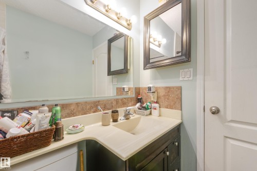 Bathroom vanity with integrated sink, light-colored countertop, and dark wood-finish cabinetry - 17328 106 Street, Edmonton, AB 