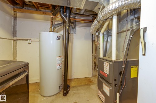Basement utility area featuring a water heater, furnace, exposed ductwork, exposed copper piping, and concrete flooring - 17328 106 Street, Edmonton, AB 