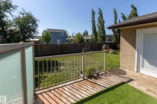 Outdoor wood deck featuring a tan metal railing with frosted privacy panels and a white patio door - 17328 106 Street, Edmonton, AB 