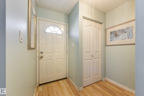 Entryway featuring light wood-finish flooring, a white paneled door with an arched window insert, and a bi-fold closet door - 17328 106 Street, Edmonton, AB 