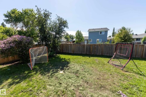Expansive backyard featuring a natural grass lawn, wood privacy fencing, and mature perimeter trees - 17328 106 Street, Edmonton, AB 