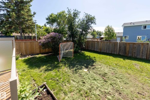 Spacious backyard featuring a full wood privacy fence, mature trees, and a ground-level wood deck - 17328 106 Street, Edmonton, AB 
