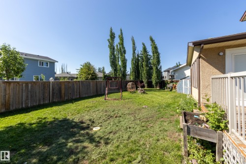 Expansive backyard featuring a privacy fence, established lawn, raised planter box, and a ground-level patio - 17328 106 Street, Edmonton, AB 