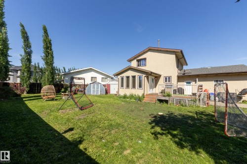 Spacious backyard featuring a multi-level deck, stucco exterior, and mature trees along the perimeter - 17328 106 Street, Edmonton, AB 