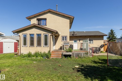 Rear exterior featuring a stucco finish, multi-level wood deck, sunroom addition with multiple windows, and a detached storage shed - 17328 106 Street, Edmonton, AB 