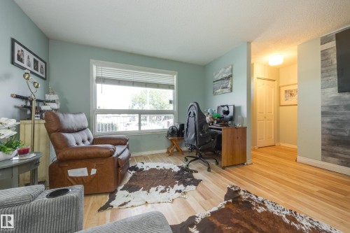 Light-toned wood-finish flooring complements the pale blue wall color in this versatile room - 17328 106 Street, Edmonton, AB 