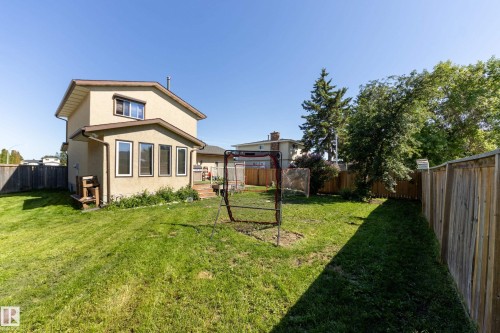 Expansive backyard with a manicured lawn, established trees, and perimeter wood fencing - 17328 106 Street, Edmonton, AB 