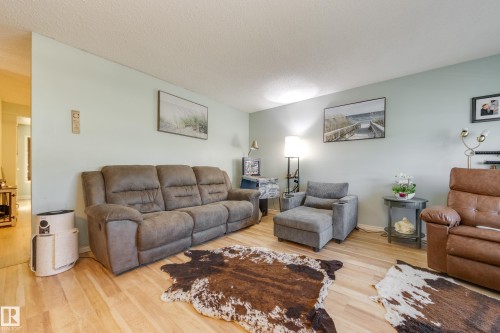 Spacious living area featuring light wood-finish flooring, soft green walls, and a recessed ceiling - 17328 106 Street, Edmonton, AB 