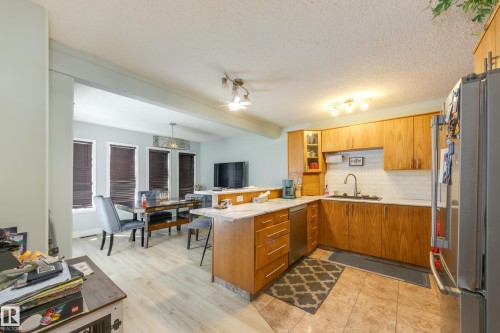 Kitchen and dining area featuring wood-finish cabinetry, stainless steel appliances, and a white subway tile backsplash - 17328 106 Street, Edmonton, AB 