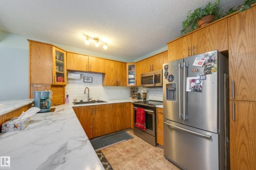 Kitchen featuring wood cabinetry, white subway tile backsplash, and light-toned countertops - 17328 106 Street, Edmonton, AB 