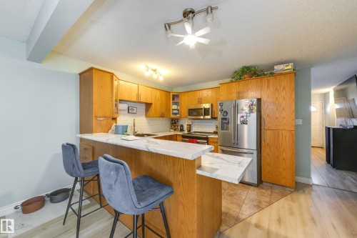 Kitchen featuring light wood cabinetry, white marble-look countertops, and stainless steel appliances - 17328 106 Street, Edmonton, AB 