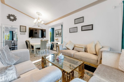 Living area featuring vaulted ceilings, a central chandelier, and white wall finishes - 7920 7 Avenue, Edmonton, AB 