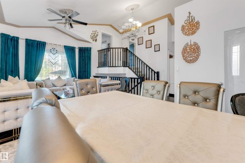 Open-concept living and dining area featuring vaulted ceilings, a contemporary ceiling fan, and a chandelier with decorative medallions - 7920 7 Avenue, Edmonton, AB 