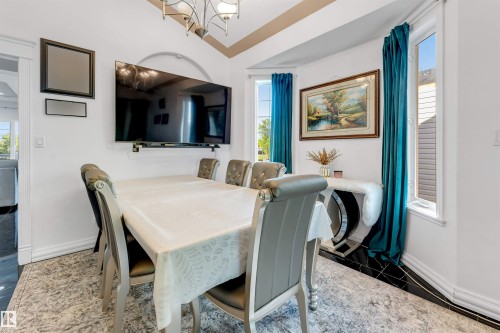 Dining area featuring dark tile flooring, white walls, and a bay window with teal drapery - 7920 7 Avenue, Edmonton, AB 