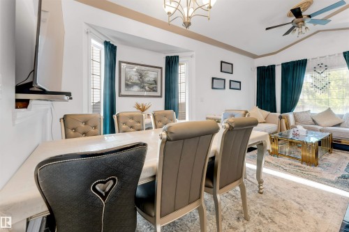 Combined living and dining area featuring a vaulted ceiling, ceiling fan, and decorative chandelier - 7920 7 Avenue, Edmonton, AB 