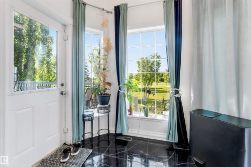Entryway with glossy black flooring and white paneled door - 7920 7 Avenue, Edmonton, AB 